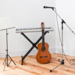 Musical instruments in a room. Electric piano, guitar, microphone and stand with sheet music.